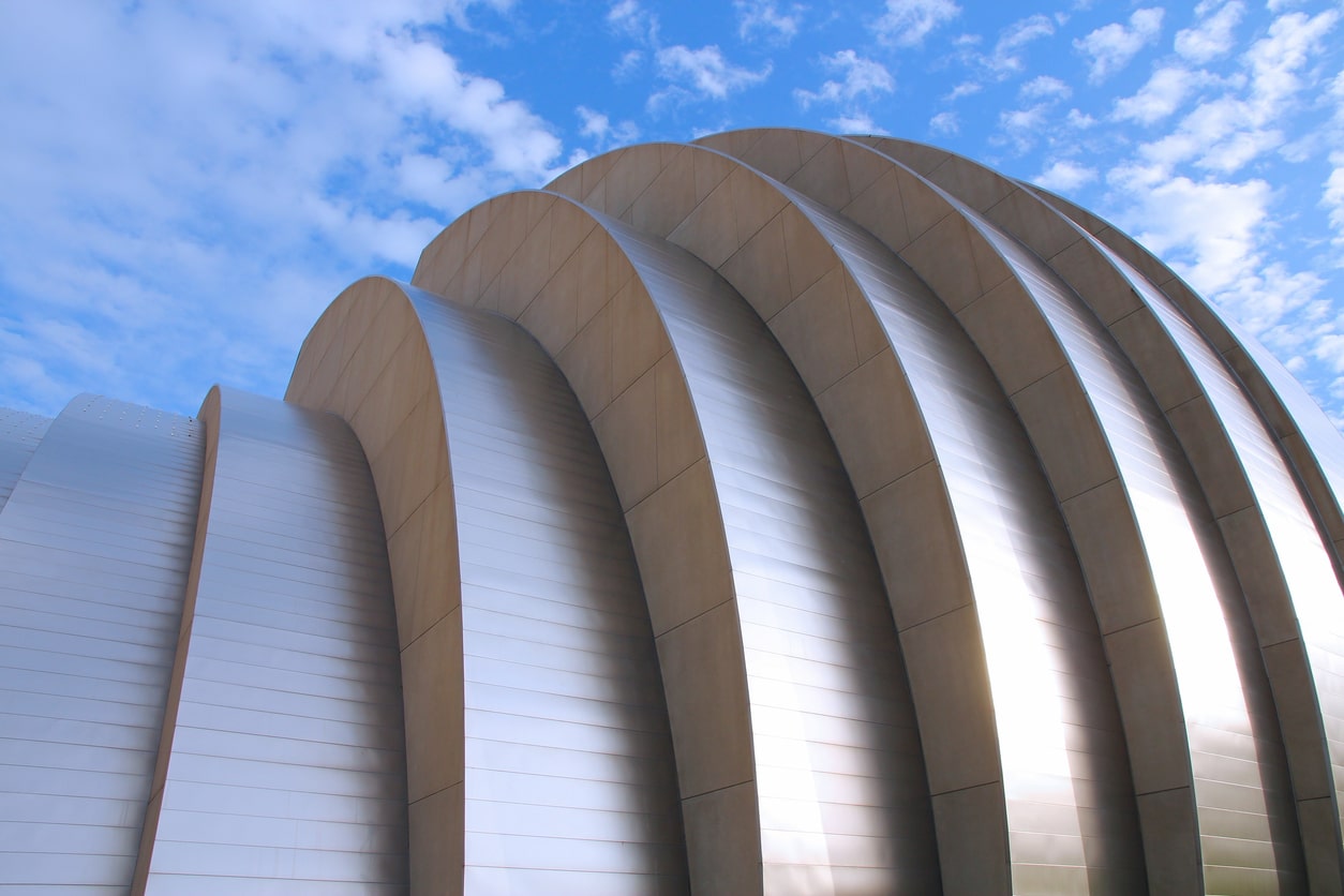 The round side of the Kauffman Center in Kansas City, Missouri, shimmers just below a cloudy blue sky.