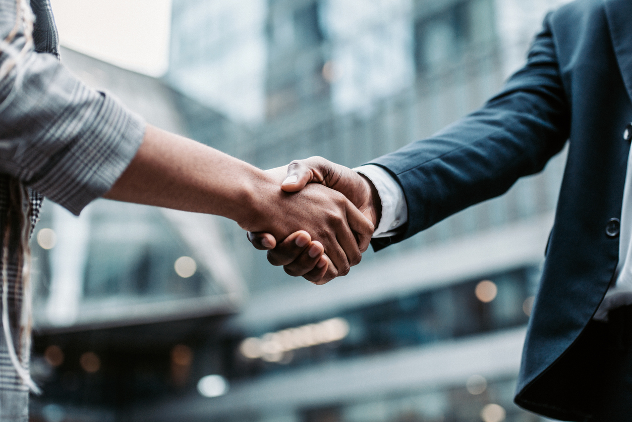 Two business persons shaking hands standing outside